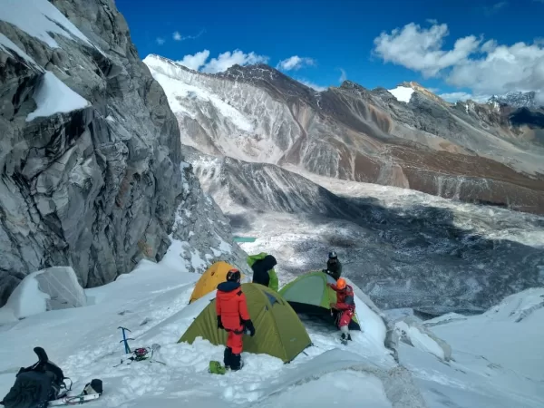 High-altitude mountaineers setting up tents on snowy slope during Larkya Peak climb in Manaslu region, Nepal, with panoramic Himalayan mountain views